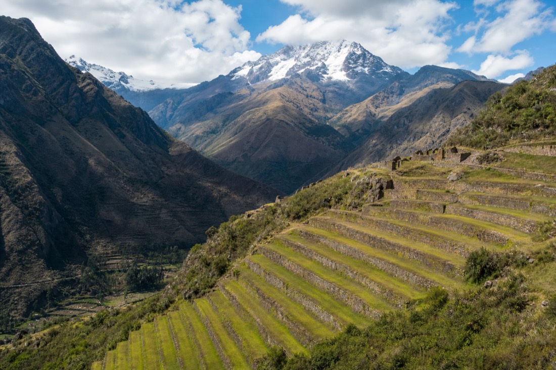 Stone Inca terraces stepping down a Sacred Valley hillside with snow-capped peaks behind
