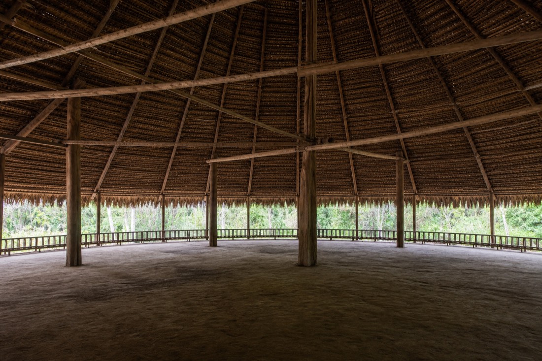 Large open-sided ceremonial maloca with woven roof beams in soft morning light, Peruvian Amazon