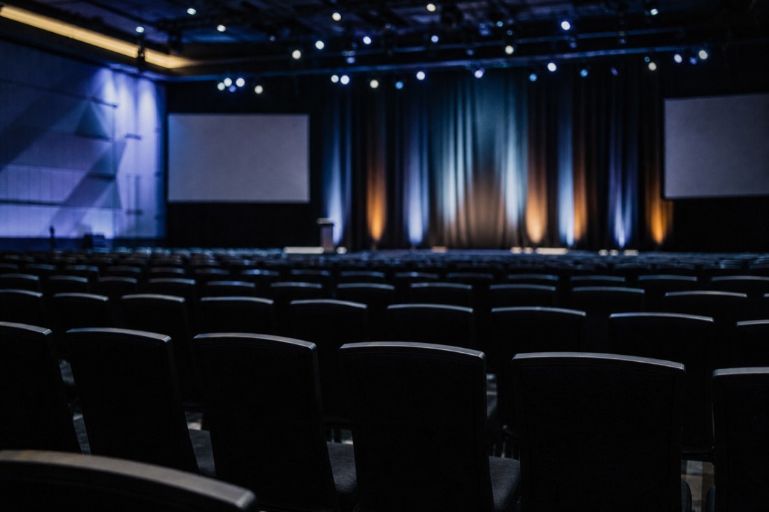 Rows of empty auditorium seats under stage lighting before a conference talk