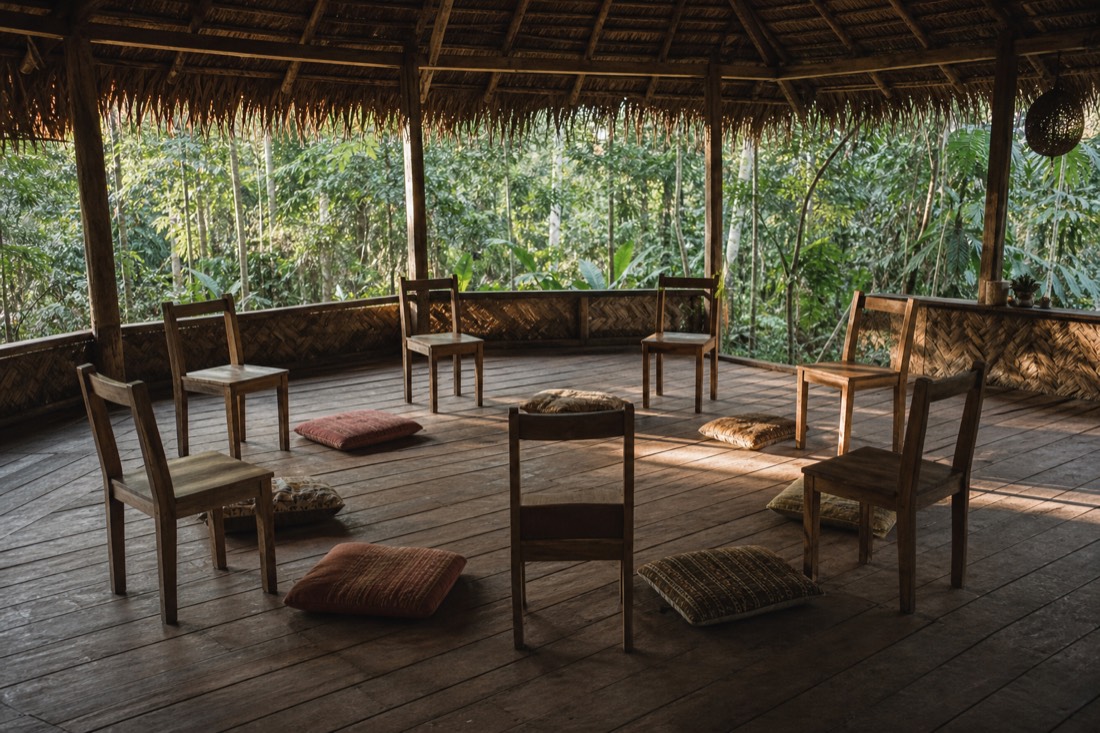 Small group of chairs arranged in a circle inside an open-sided maloca in the jungle near Tamshiyacu, morning light