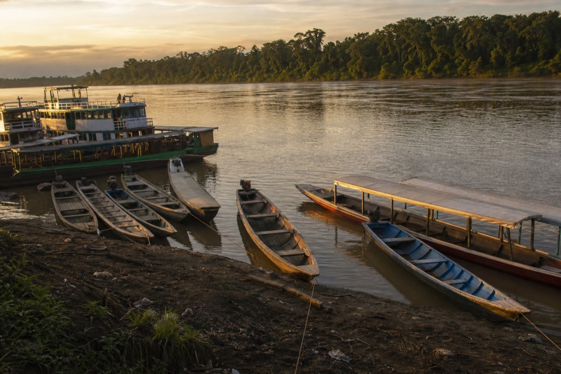Wooden boats moored along a busy Amazon riverfront at dawn near Iquitos