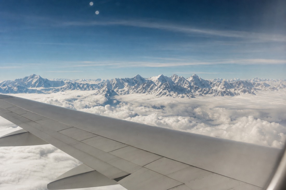 Airplane wing above dense white clouds over the Andes in clear high-altitude light