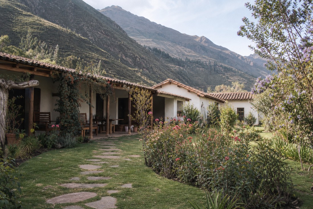 Quiet adobe courtyard of a generic Andean retreat with mountains behind, typical of Sacred Valley ayahuasca centers